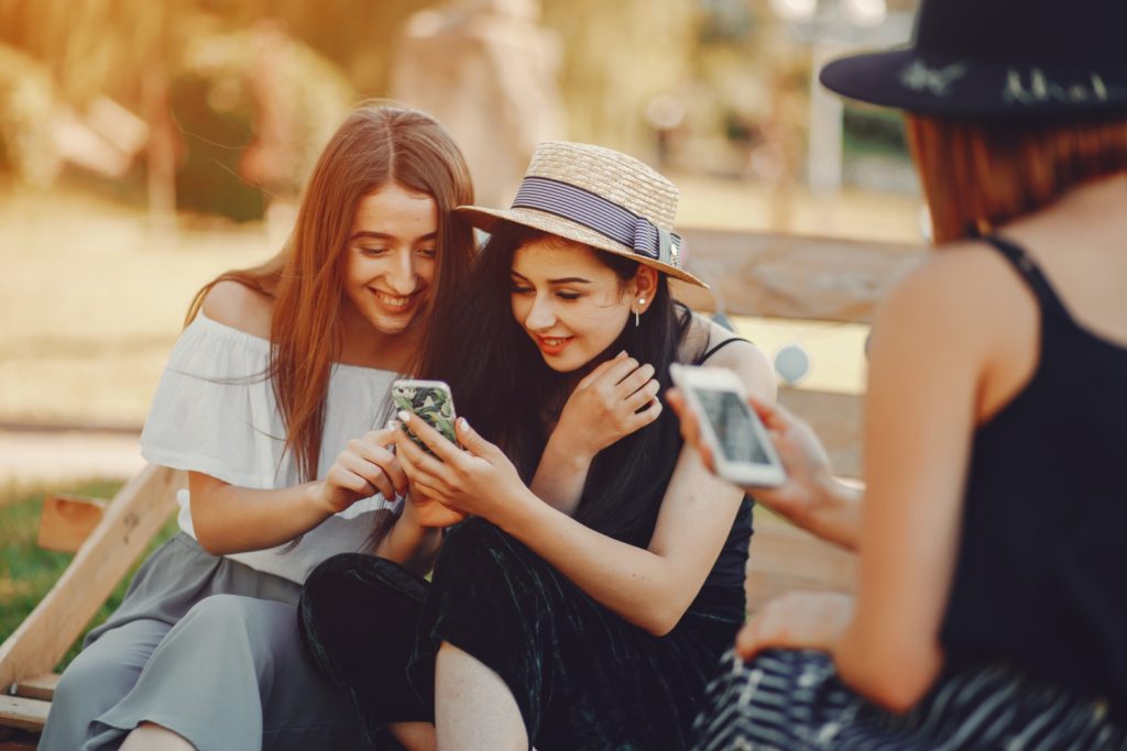 Group of friends outdoors looking at phones together, enjoying travel connection